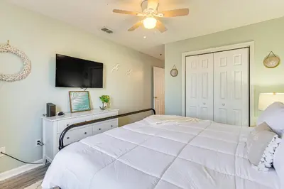 a bedroom with a white bed and a ceiling fan at Walk to Beach Condo with Balcony in PCB! in Panama City Beach