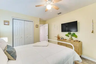 a bedroom with a white bed and a flat screen tv at Walk to Beach Condo with Balcony in PCB! in Panama City Beach