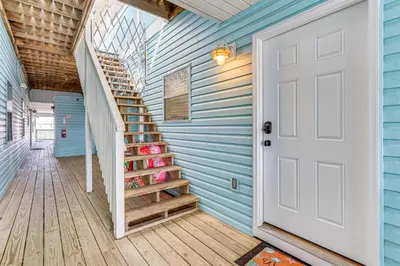 a staircase in a blue house with a white door at Walk to Beach Condo with Balcony in PCB! in Panama City Beach