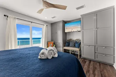 a bedroom with a blue bed with a view of the ocean at Dreamscape 30! Luxury Beach Front Property! in Panama City Beach