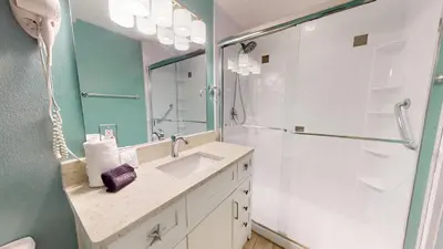 a bathroom with a shower and a sink and a mirror at Tidewater 1003 in Panama City Beach