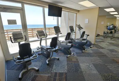 a gym with chairs and a large window with the ocean at Tidewater 1003 in Panama City Beach