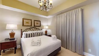 a bedroom with a bed with white sheets and a chandelier at Calypso I 407E in Panama City Beach