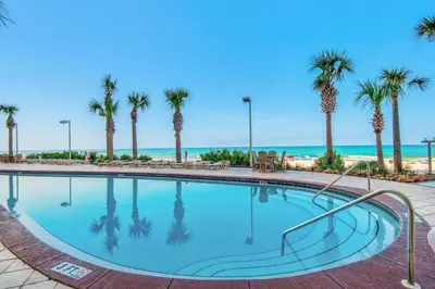a swimming pool with palm trees and the beach at Calypso I 407E in Panama City Beach
