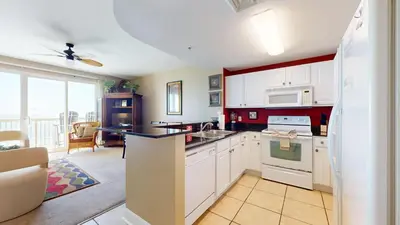 a kitchen with white cabinets and a large window at Calypso I 407E in Panama City Beach