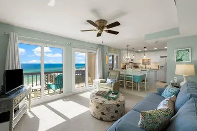 a living room with a blue couch and a view of the ocean at Fabulous 3-Bed 3-Bath Condo with Private Covered Parking Space! in Panama City Beach