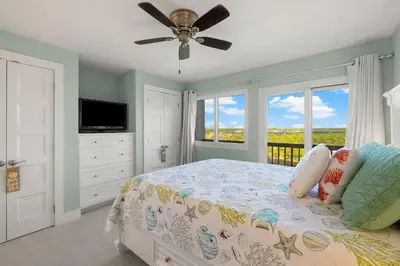 a bedroom with a bed with a ceiling fan and a window at Fabulous 3-Bed 3-Bath Condo with Private Covered Parking Space! in Panama City Beach