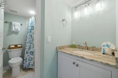 a white bathroom with a toilet and a sink at Fabulous 3-Bed 3-Bath Condo with Private Covered Parking Space! in Panama City Beach
