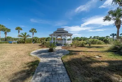 a gazebo in a park with palm trees at Fabulous 3-Bed 3-Bath Condo with Private Covered Parking Space! in Panama City Beach