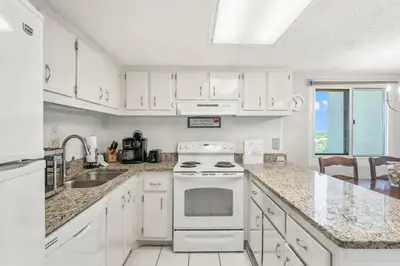 a white kitchen with a stove and a sink at Beautiful Gulf and Lake views from Pinnacle Port A-935! in Panama City Beach