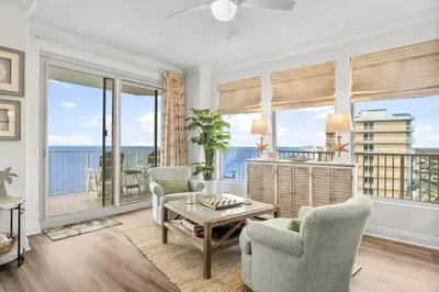 a living room with a table and chairs and windows at Treasure Island #2112 in Panama City Beach