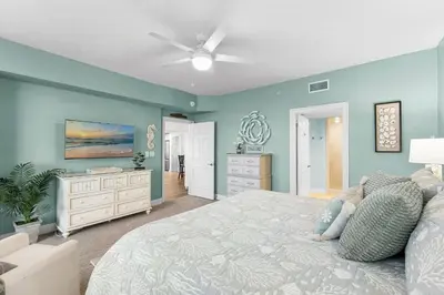 a bedroom with a large bed and blue walls at Treasure Island #2112 in Panama City Beach