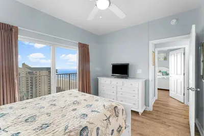 a bedroom with a bed and a television and a balcony at Shores Of Panama #1224 in Panama City Beach