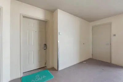 an empty room with a door and a green rug at Aqua 511 in Panama City Beach