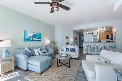 a living room with blue and white furniture and a kitchen at Aqua 511 in Panama City Beach