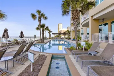 a swimming pool with chaise lounge chairs and palm trees at Aqua 511 in Panama City Beach