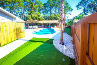 a yard with a pool and a fence with a putting green at Panhandle Paradise, Heated Pool, Hot Tub, Mini & Disc Golf, Game Room in Panama City Beach