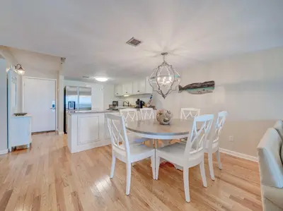 a kitchen and dining room with a table and chairs at Sandy Bottoms PPC3 - 401! Gulf Front Views! in Panama City Beach