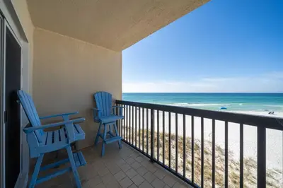 two blue chairs on a balcony overlooking the beach at Sandy Bottoms PPC3 - 401! Gulf Front Views! in Panama City Beach