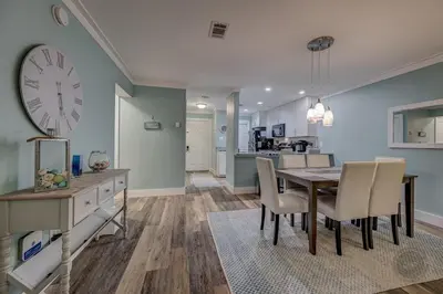 a dining room with a table and a clock on the wall at Our Happy Place! Seasonal Beach SRV! Pool & Gulf Views! in Panama City Beach