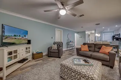 a living room with a couch and a flat screen tv at Our Happy Place! Seasonal Beach SRV! Pool & Gulf Views! in Panama City Beach