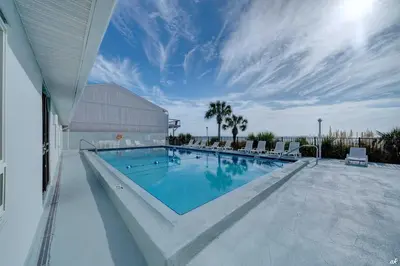 a large swimming pool with chairs and a building at Toes in the Sand at Shores #101 in Panama City Beach