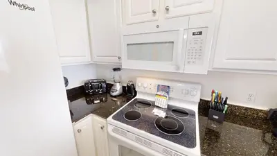 a white kitchen with a stove and a microwave at Sunrise Beach 2007 in Panama City Beach