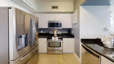 a kitchen with white cabinets and a stainless steel refrigerator at Emerald Beach 1835 in Panama City Beach