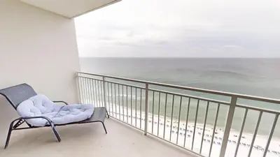 a chair on a balcony with a view of the ocean at Emerald Beach 1835 in Panama City Beach