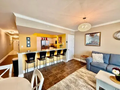 a living room with a couch and a bar at Emerald Beach 1935 in Panama City Beach