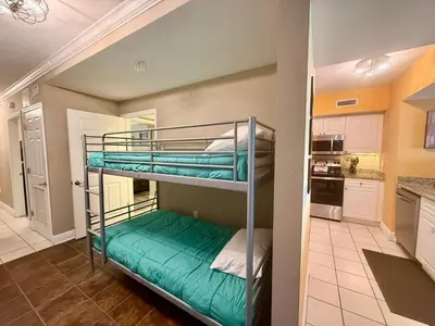 two bunk beds in a room with a kitchen at Emerald Beach 1935 in Panama City Beach