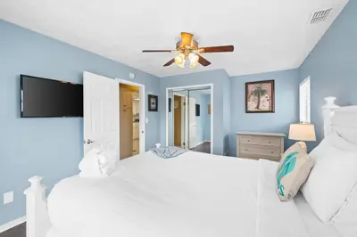 a bedroom with a white bed and a ceiling fan at Lagoon Cocune by Book That Condo in Panama City Beach