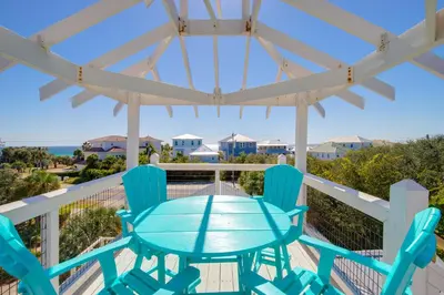 a table and chairs on a deck with a view of the ocean at Pool On 30A Gulf Views Balconies Luxury in Inlet Beach