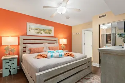 a bedroom with a bed with orange walls at Emerald Beach Resort 234 | Roo’s Rendezvous in Panama City Beach