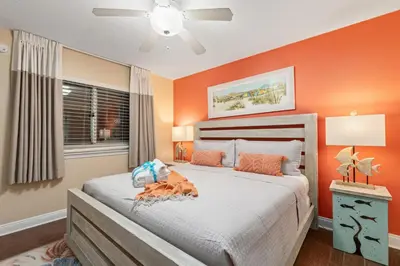 a bedroom with orange walls and a large bed at Emerald Beach Resort 234 | Roo’s Rendezvous in Panama City Beach