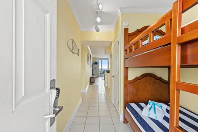 a bedroom with bunk beds and a hallway at Emerald Beach Resort 1431 | Tucker’s Tondo in Panama City Beach