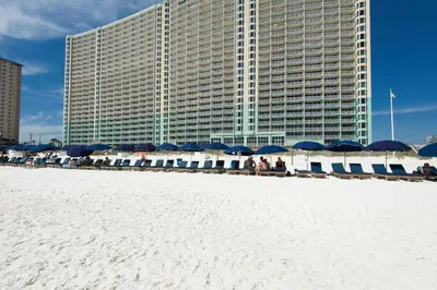 a building with blue and white umbrellas on the beach at Emerald Beach Resort 1431 | Tucker’s Tondo in Panama City Beach