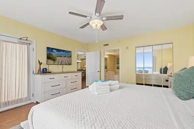a bedroom with a white bed with a ceiling fan at Emerald Beach Resort 1431 | Tucker’s Tondo in Panama City Beach