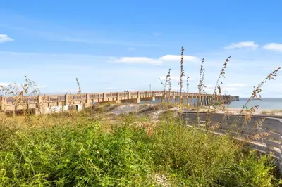a bridge over a beach next to the ocean at Emerald Beach Resort 2028 in Panama City Beach