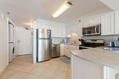 a kitchen with white cabinets and a stainless steel refrigerator at NEW 30A Beachfront Condo with Pool and 4 Beds with Gulf Views in Santa Rosa Beach
