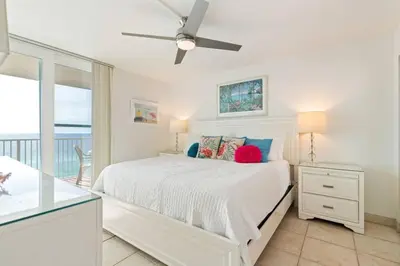 a bedroom with a white bed with a ceiling fan at NEW 30A Beachfront Condo with Pool and 4 Beds with Gulf Views in Santa Rosa Beach