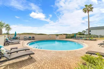 a swimming pool with chaise lounges and chairs around it at NEW 30A Beachfront Condo with Pool and 4 Beds with Gulf Views in Santa Rosa Beach