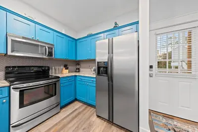 a kitchen with blue cabinets and a refrigerator at Fun Beach Condo on 30A with POOL and Lake and Beach Access in Santa Rosa Beach