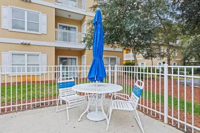 a table and chairs with a blue umbrella at Fun Beach Condo on 30A with POOL and Lake and Beach Access in Santa Rosa Beach