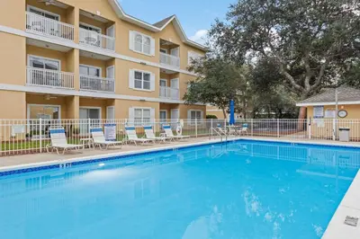 a swimming pool in front of a building with chairs at Fun Beach Condo on 30A with POOL and Lake and Beach Access in Santa Rosa Beach