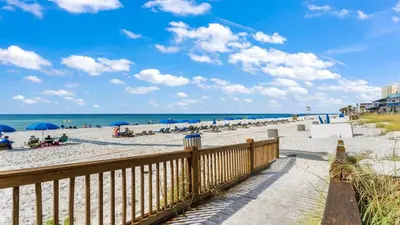 a beach with people sitting on the sand and umbrellas at The Summit 408 in Panama City Beach