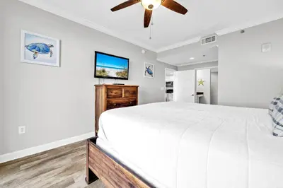 a bedroom with a white bed and a flat screen tv at Splash 1803W in Panama City Beach