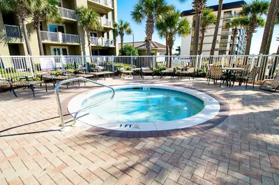 a swimming pool in a courtyard with tables and chairs at Grand Panama 1-1807 in Panama City Beach