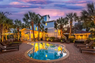 a swimming pool with chairs and a house at Tucked Away in Inlet Beach