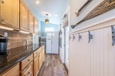 a kitchen with wooden cabinets and a white refrigerator at Tucked Away in Inlet Beach